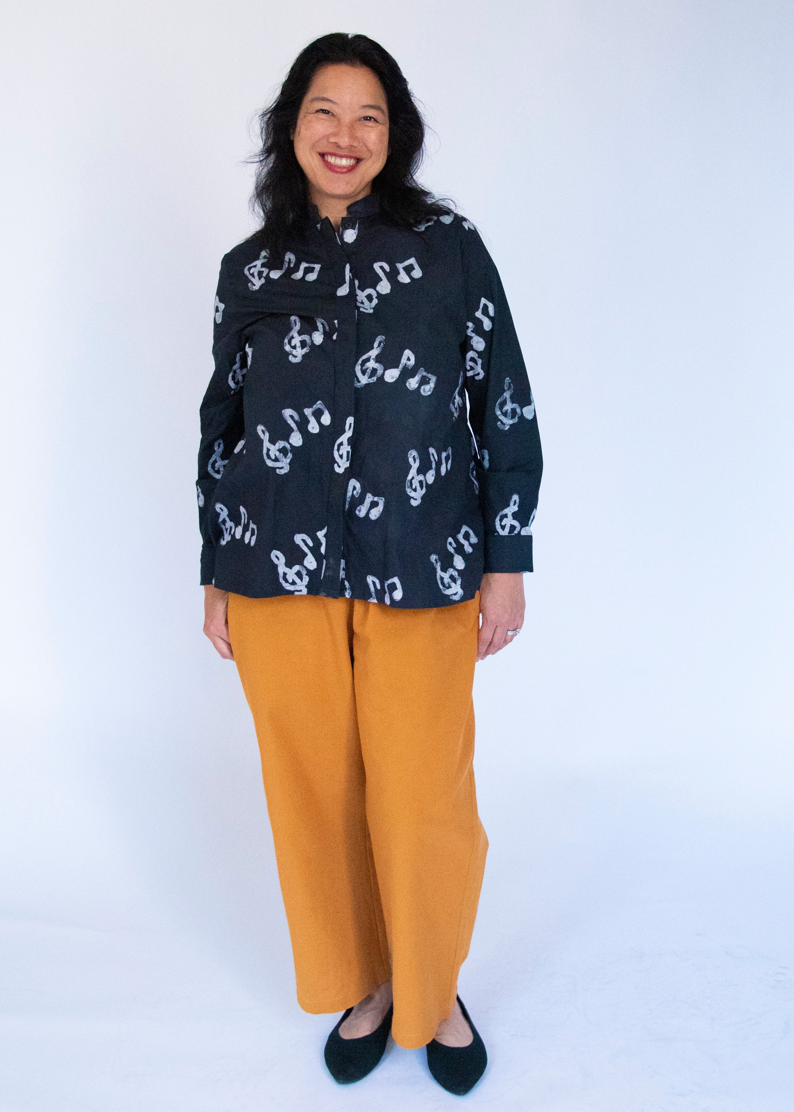 Model wearing black long sleeved shirt with white music print design.