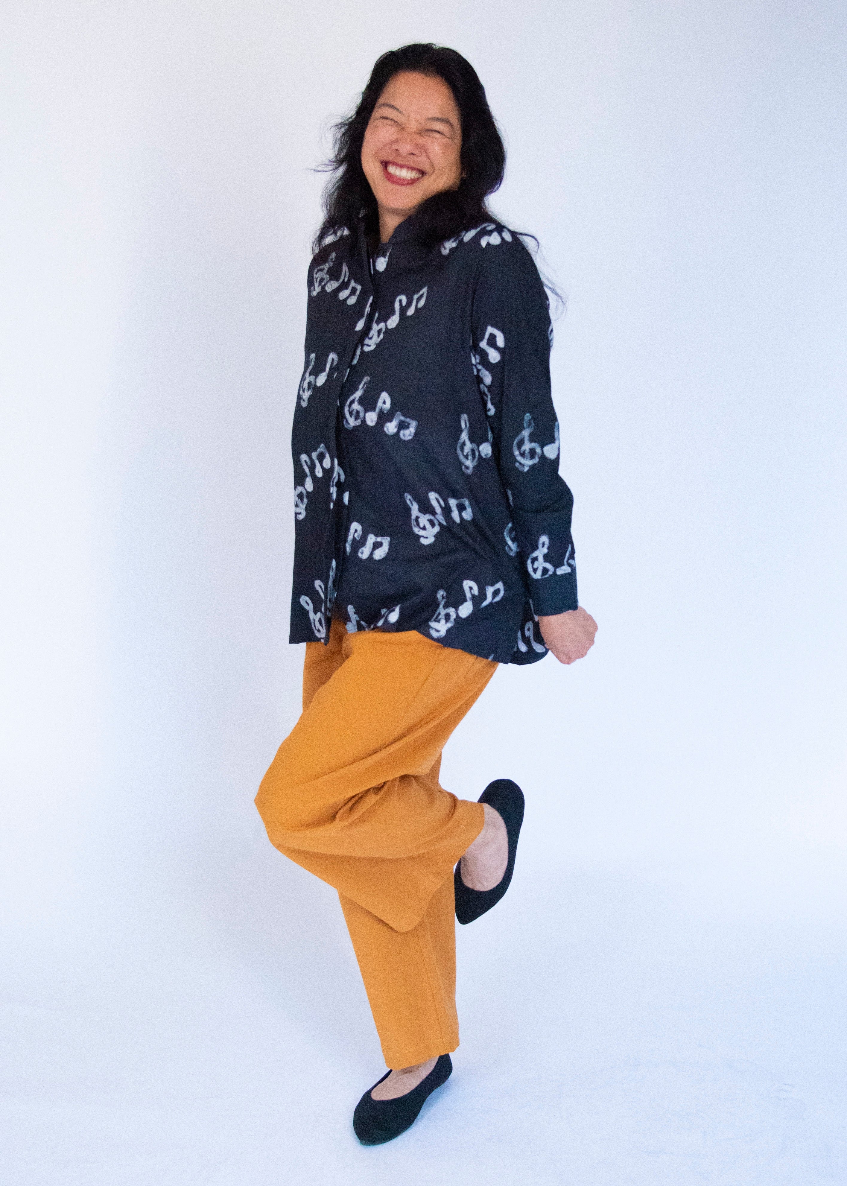 Model wearing black long sleeved shirt with white music print design.