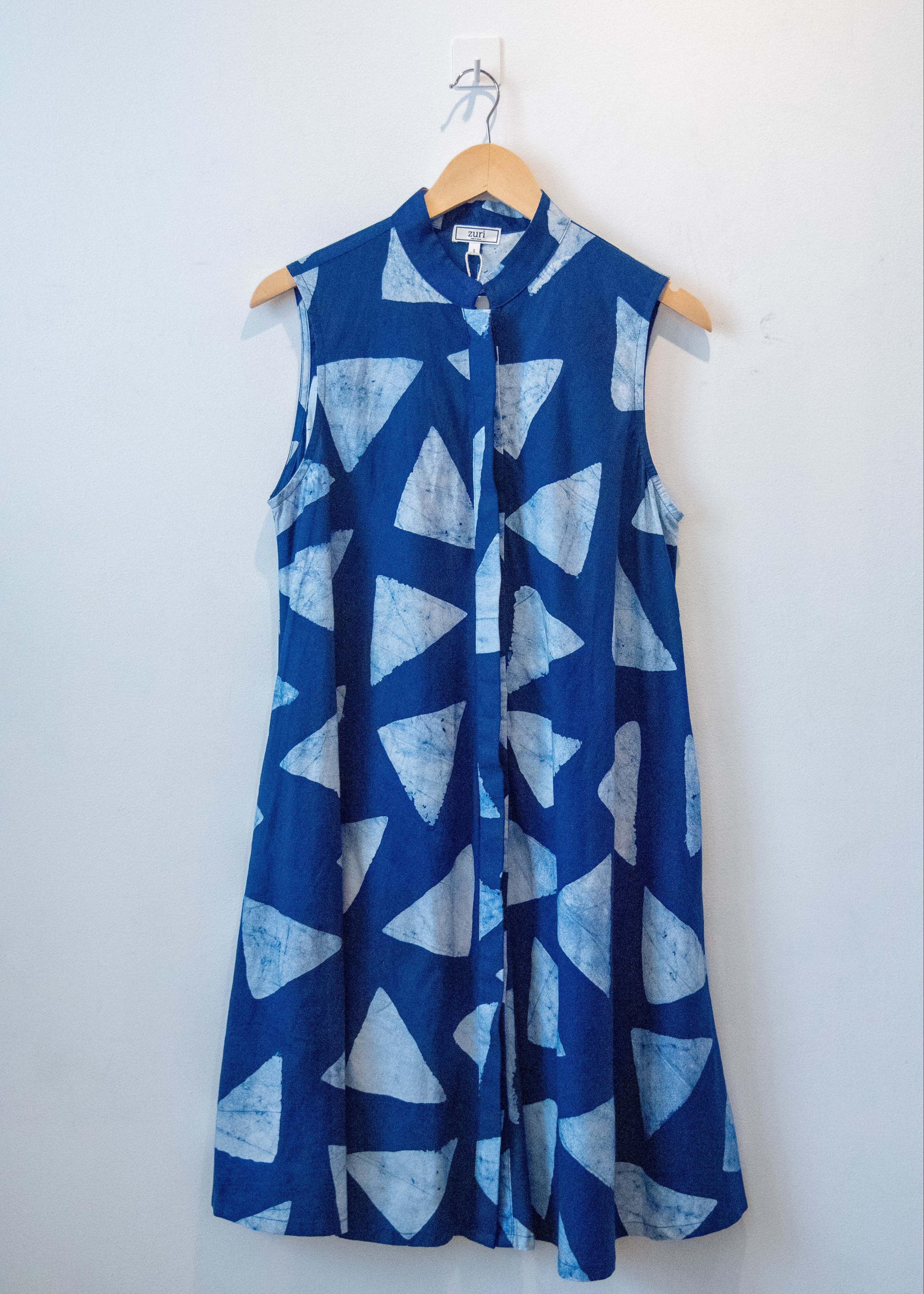 Display of blue sleeveless dress with white triangle print.