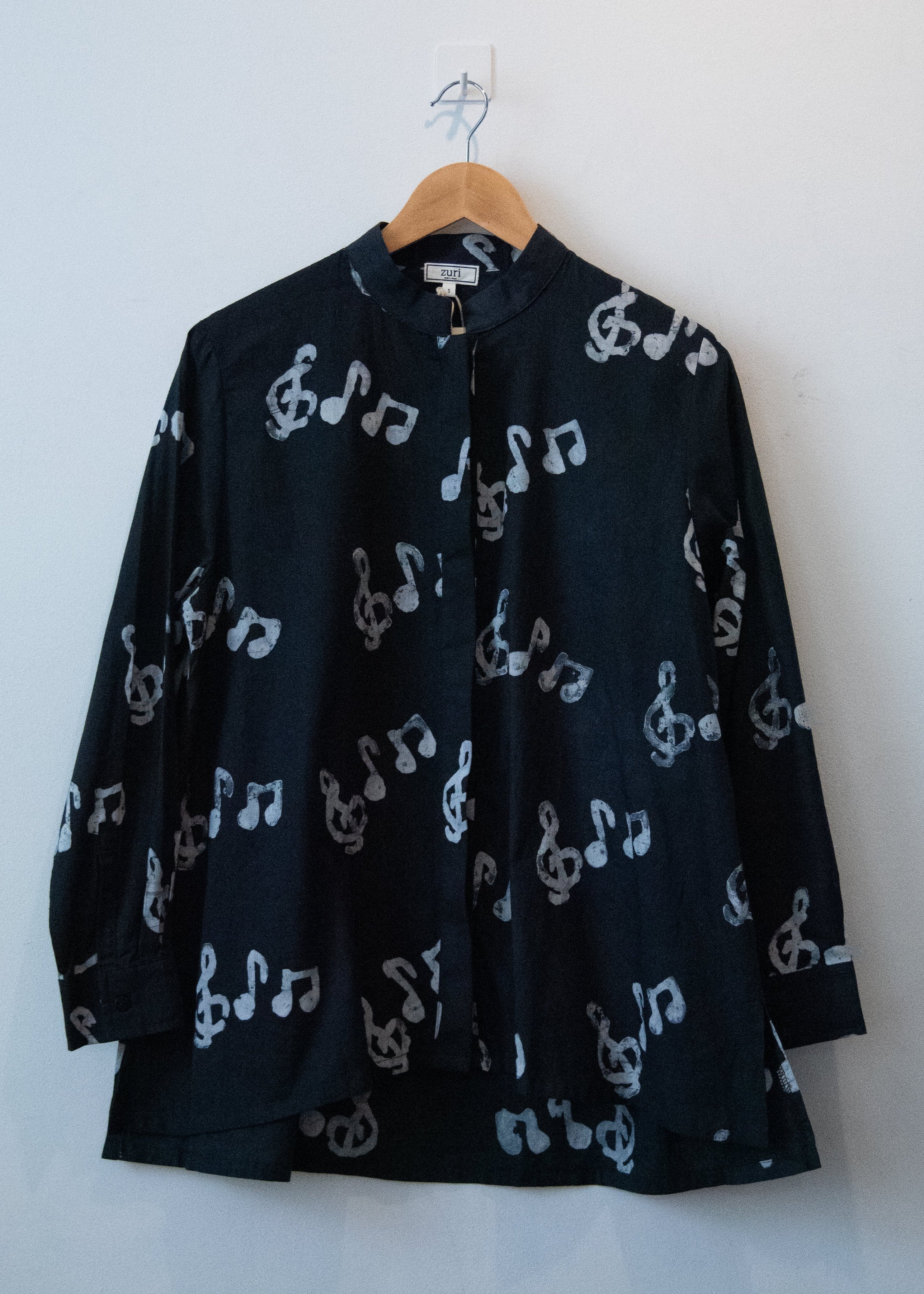Display of black long sleeved shirt with white music print design.