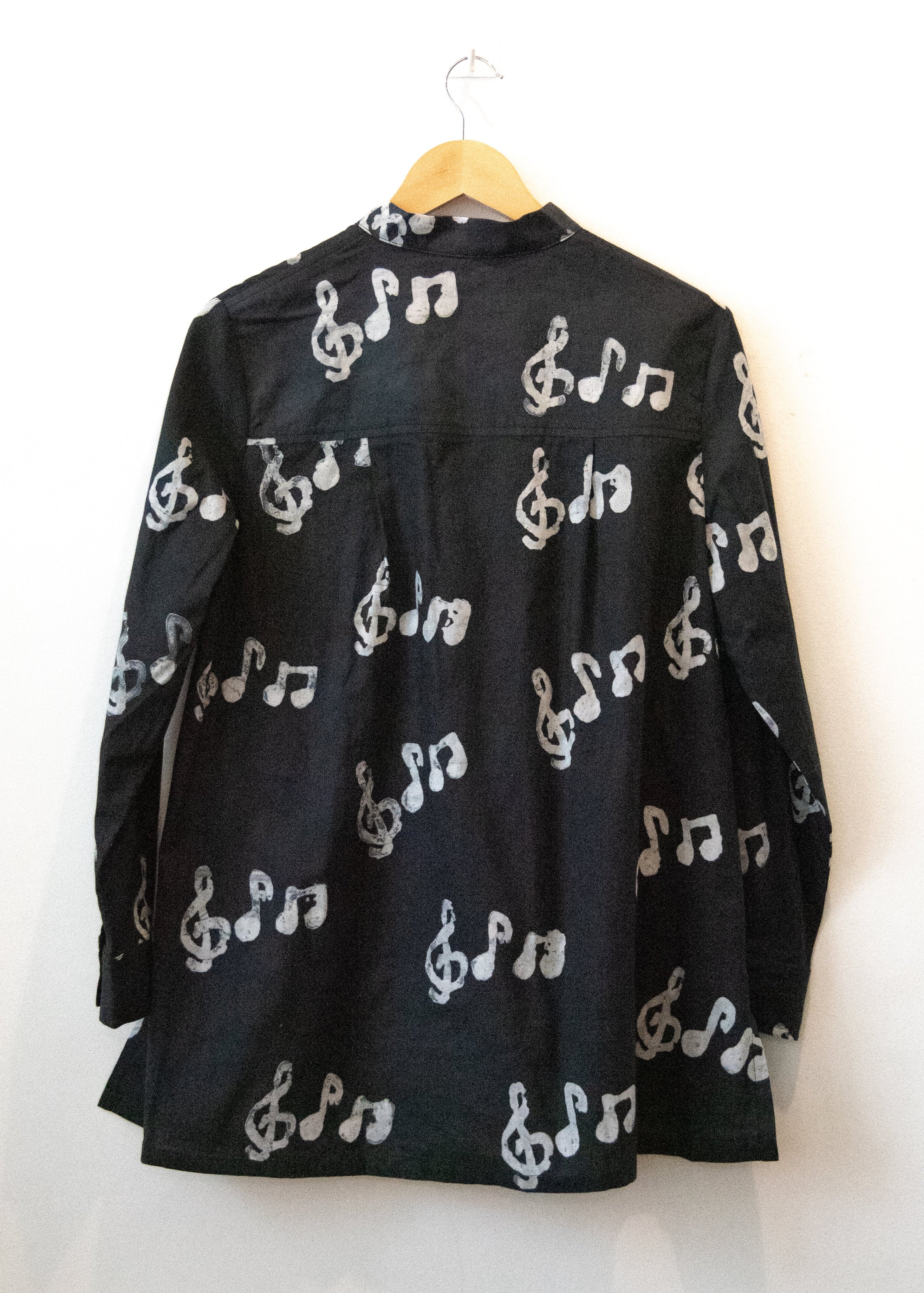 Display of black long sleeved shirt with white music print design.