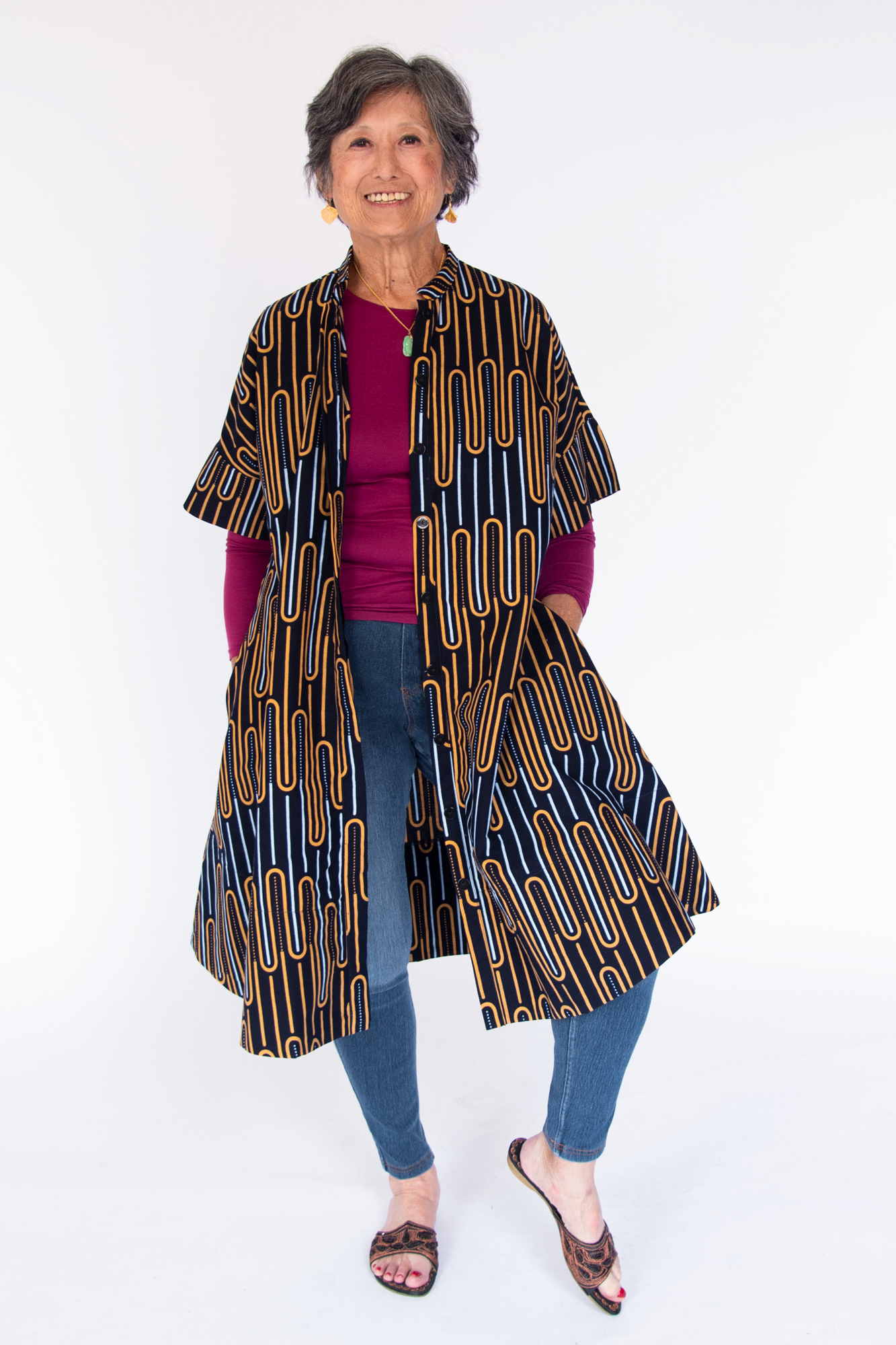 Model wearing deep navy dress with yellow and gold geometric lines.