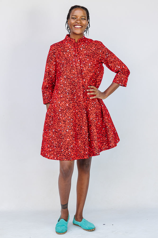 Model wearing red dress with black and white vine print.
