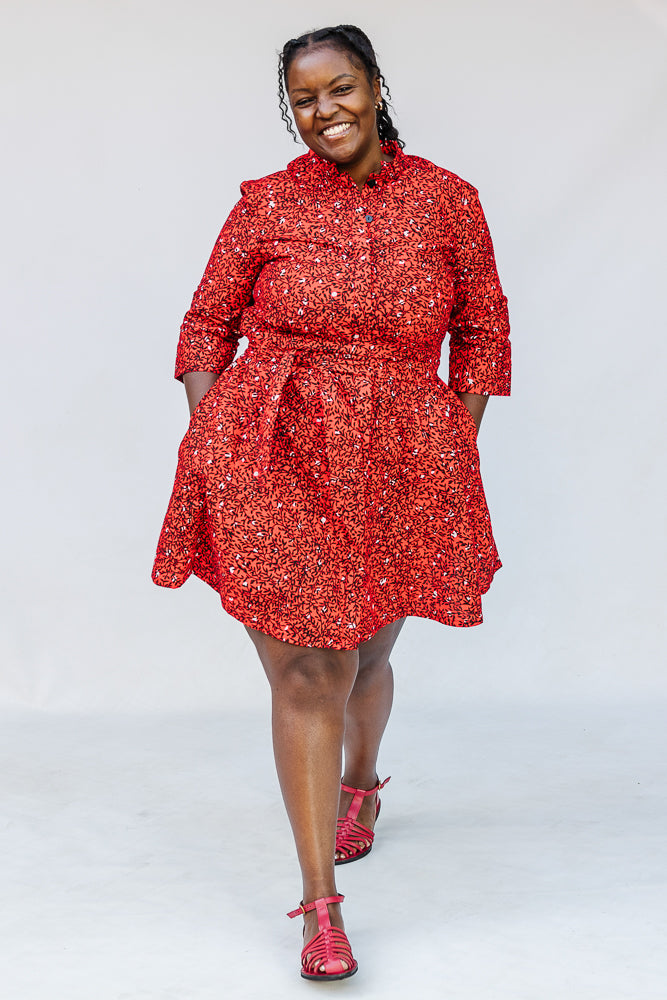 Model wearing red dress with black and white vine print.