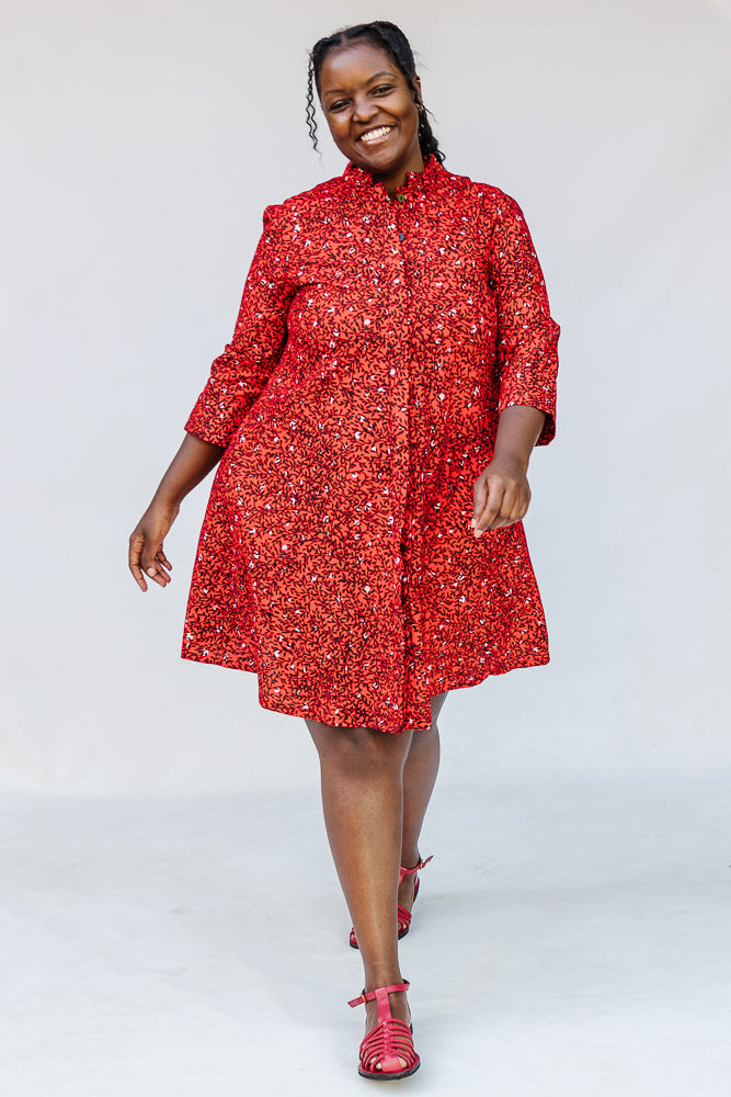 Model wearing red dress with black and white vine print.