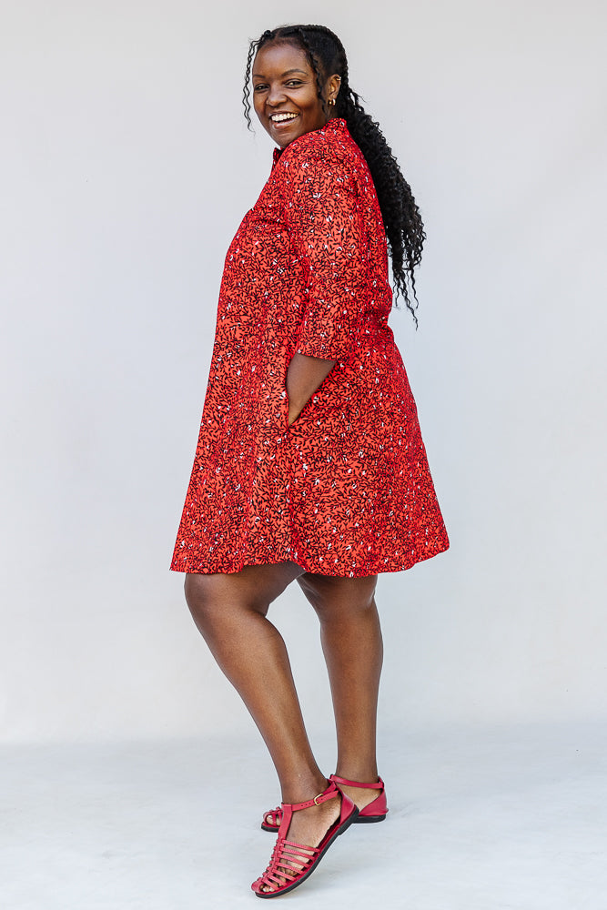 Model wearing red dress with black and white vine print.