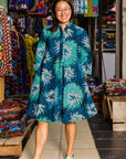 The model is wearing turquoise, black, pacific blue, slate and white feathered spiral print dress