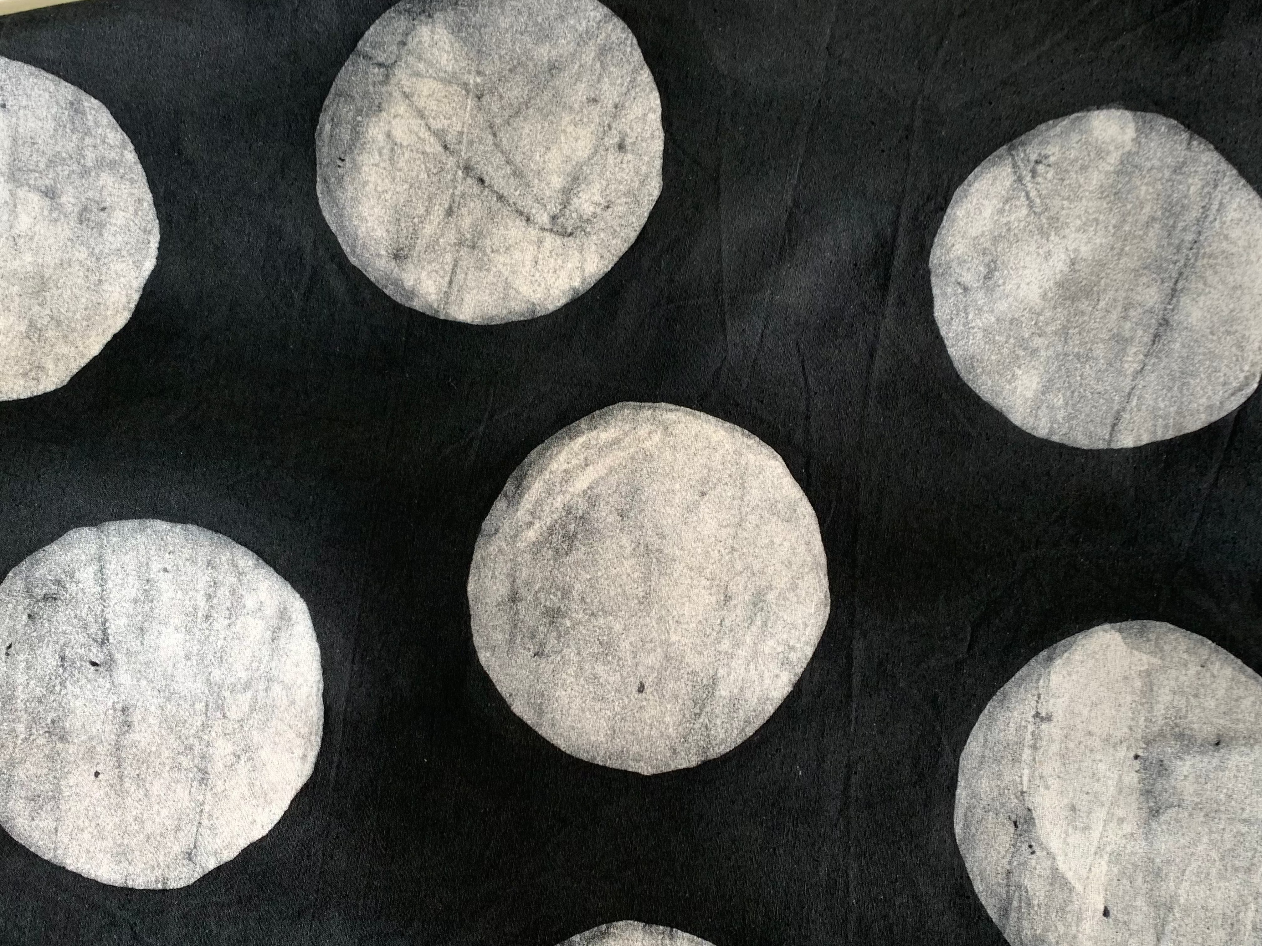 Close up display of black sleeveless shirt with white circles print, fabric.