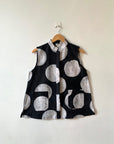 Display of black sleeveless shirt with white circles print.