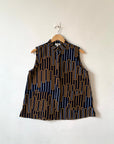 Display of sleeveless shirt with yellow and white geometric print.