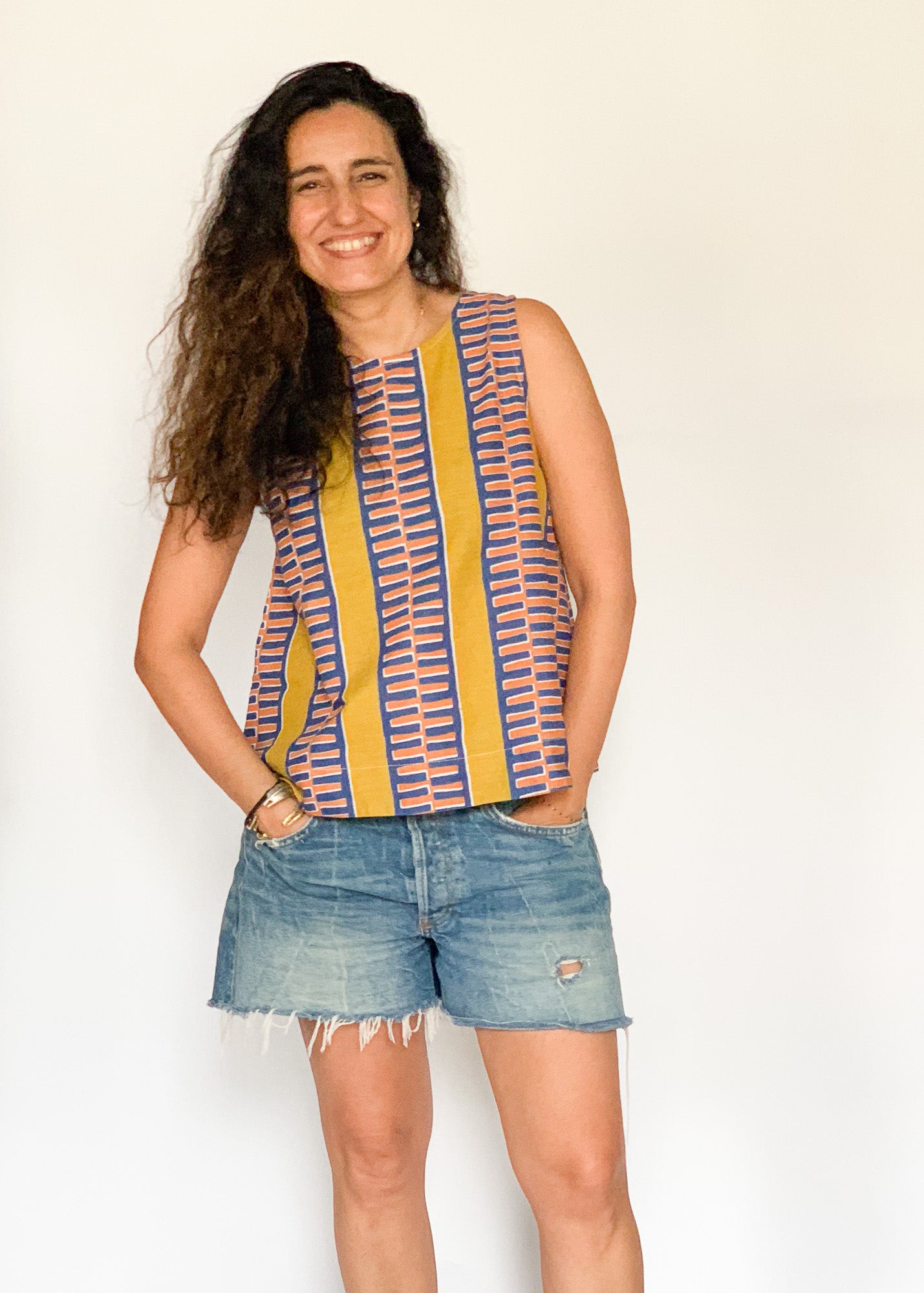 The model is wearing olive-yellow, blue, orange and white geometric printed  tank