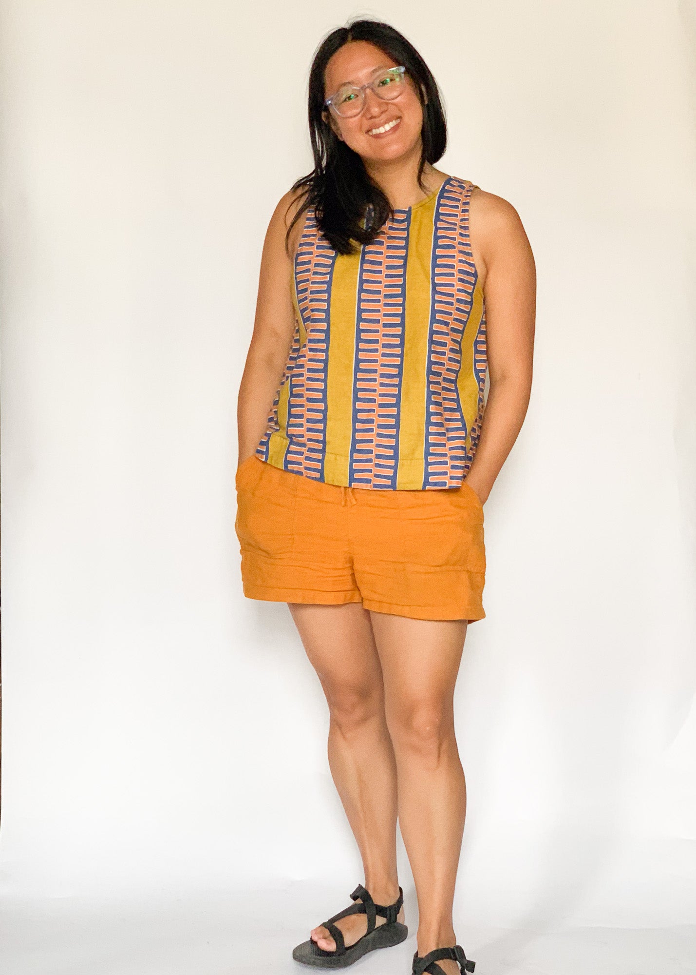 The model is wearing olive-yellow, blue, orange and white geometric printed  tank