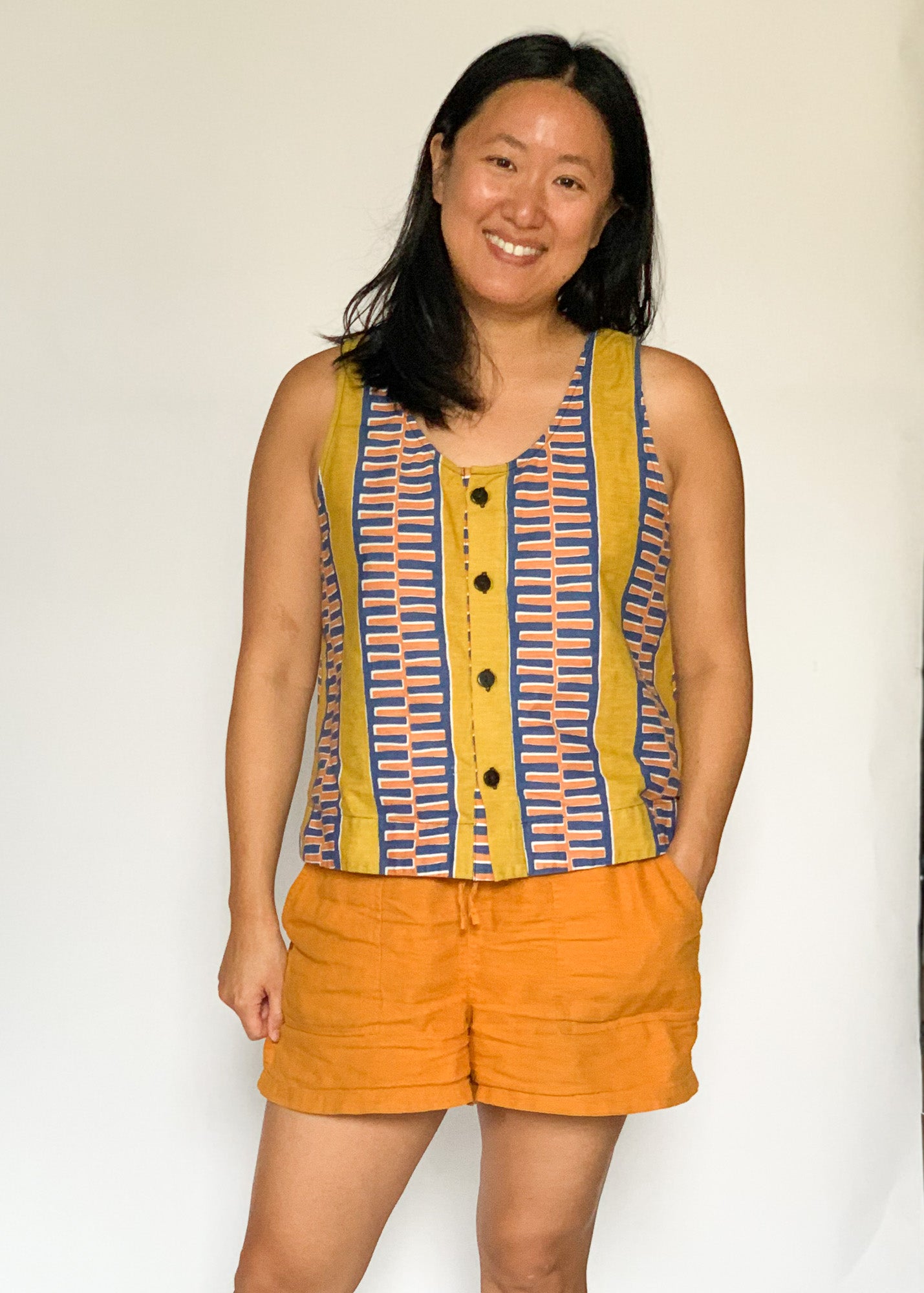 The model is wearing olive-yellow, blue, orange and white geometric printed  tank