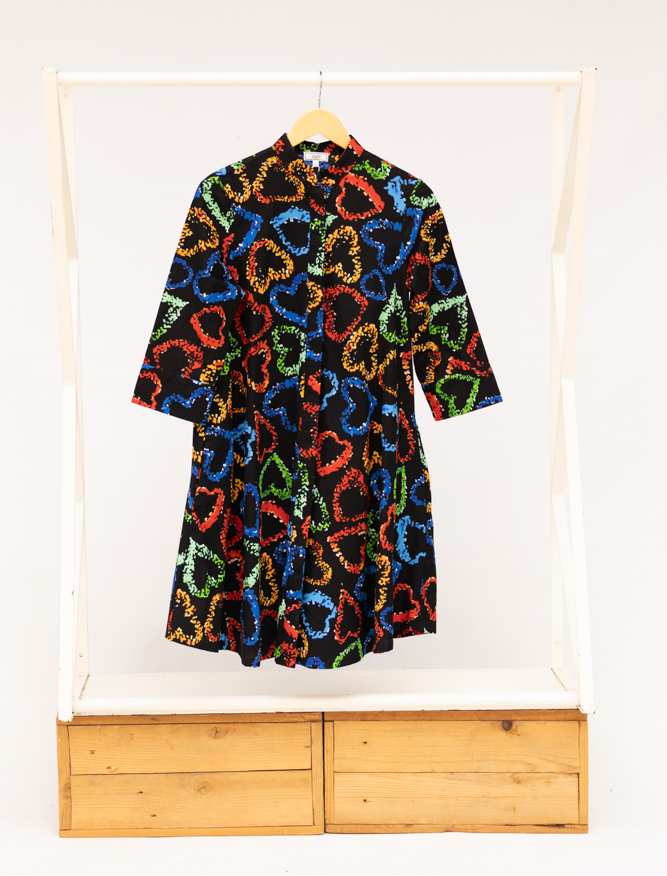 Display of black dress with multicolored heart print pattern.