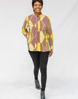 Model wearing yellow, brown and white abstract print shirt.