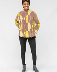 Model wearing yellow, brown and white abstract print shirt.