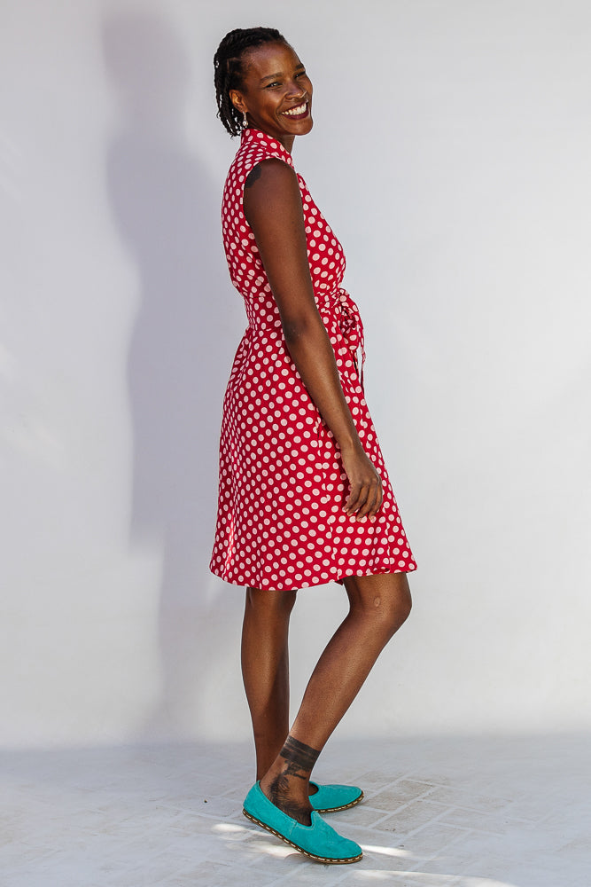 Model wearing red sleeveless dress with white dots.