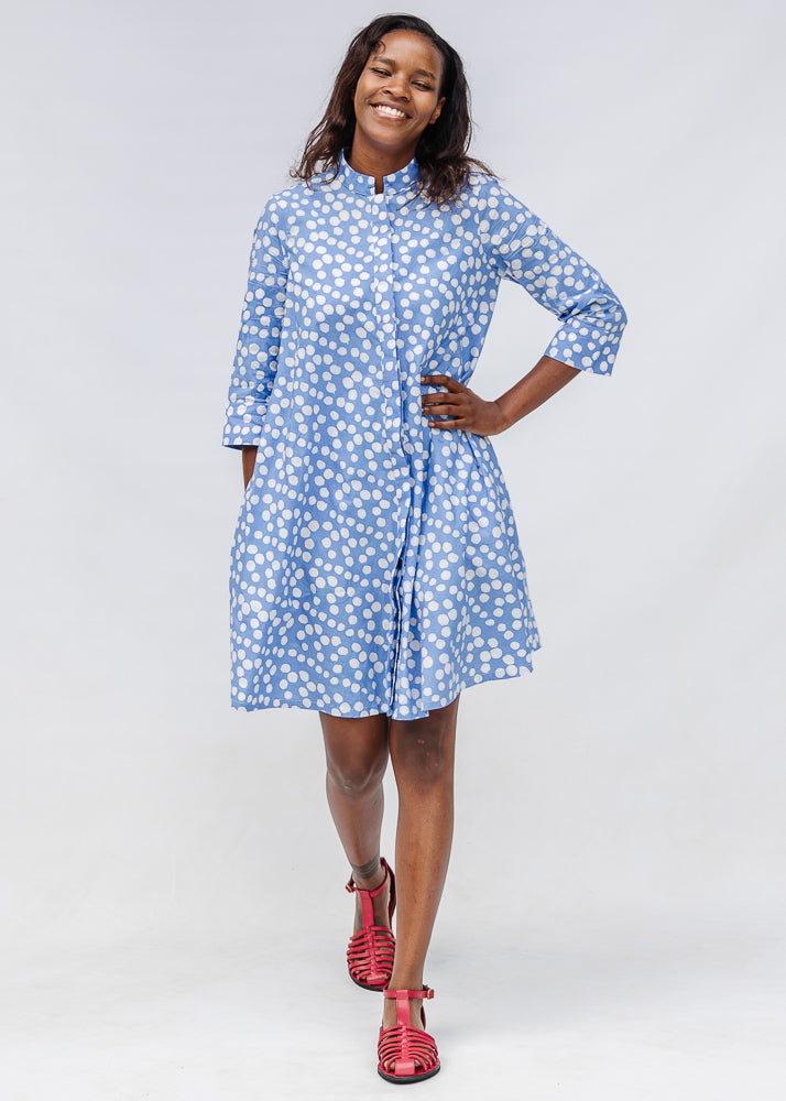 Model wearing blue dress with white polka dots.