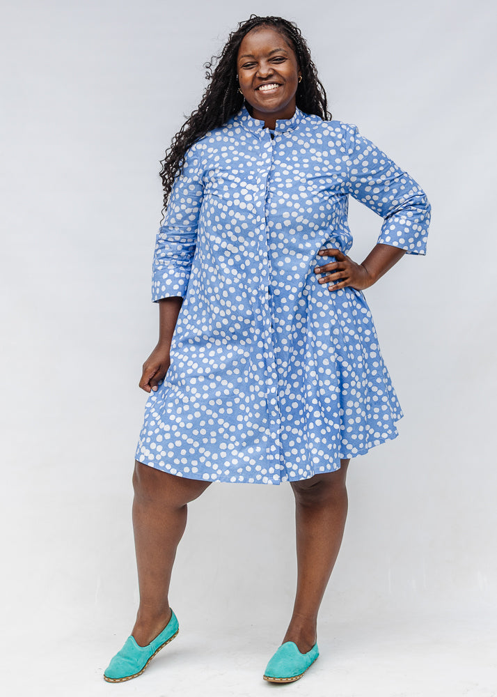 Model wearing blue dress with white polka dots.