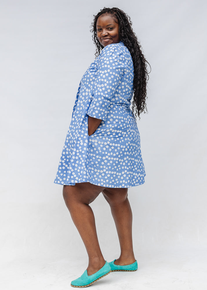 Model wearing blue dress with white polka dots.