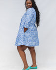 Model wearing blue dress with white polka dots.
