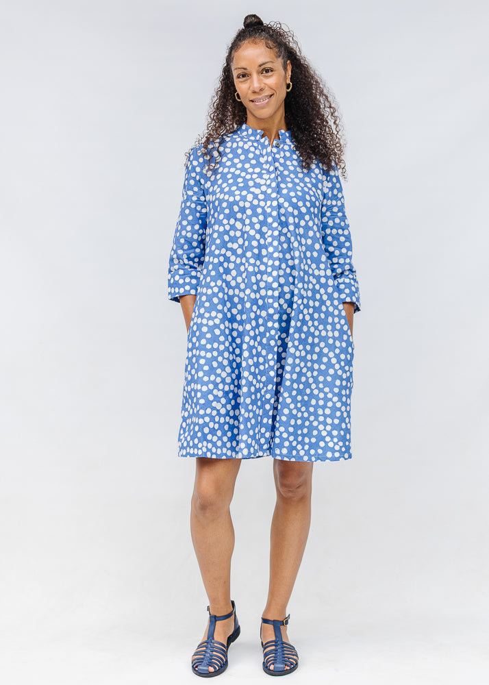 Model wearing blue dress with white polka dots.