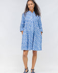 Model wearing blue dress with white polka dots.