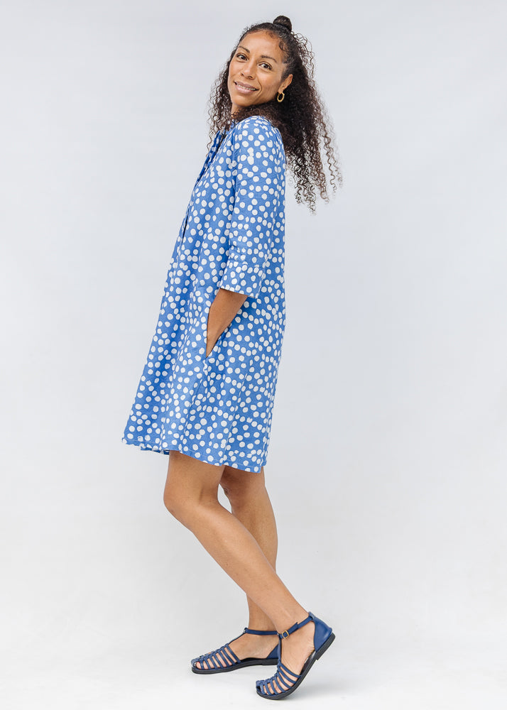 Model wearing blue dress with white polka dots.