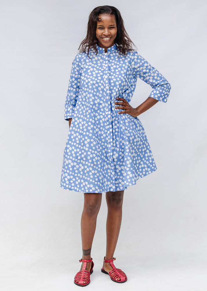 Model wearing blue dress with white polka dots.
