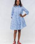 Model wearing blue dress with white polka dots.