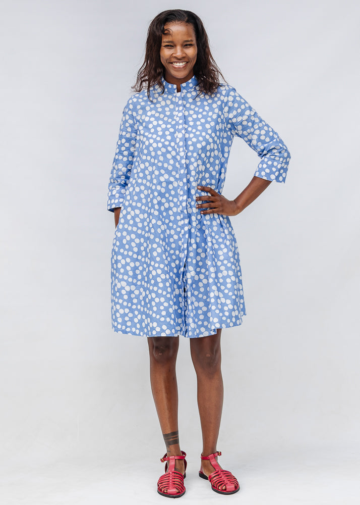Model wearing blue dress with white polka dots.