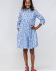 Model wearing blue dress with white polka dots.