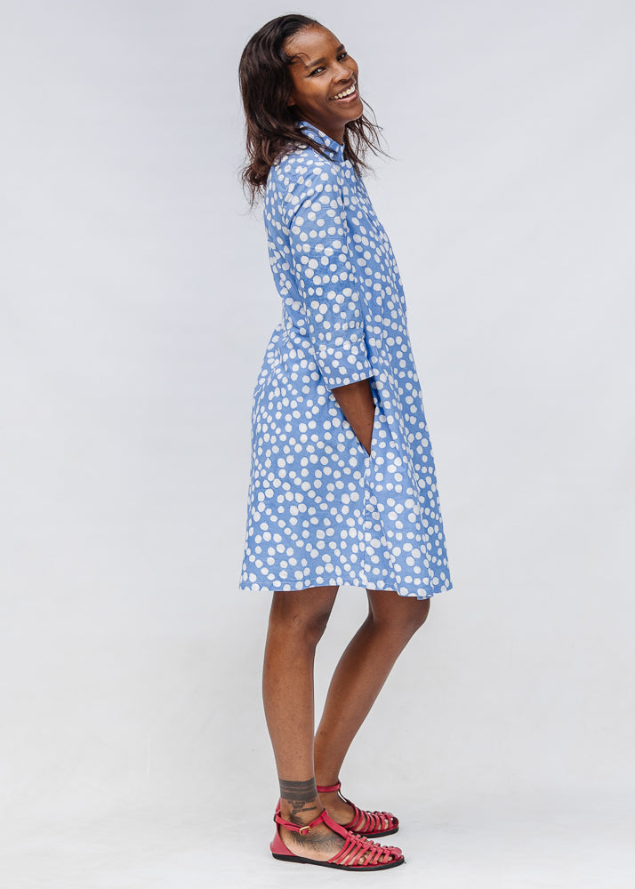 Model wearing blue dress with white polka dots.