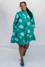 Model wearing teal dress with white cat print.