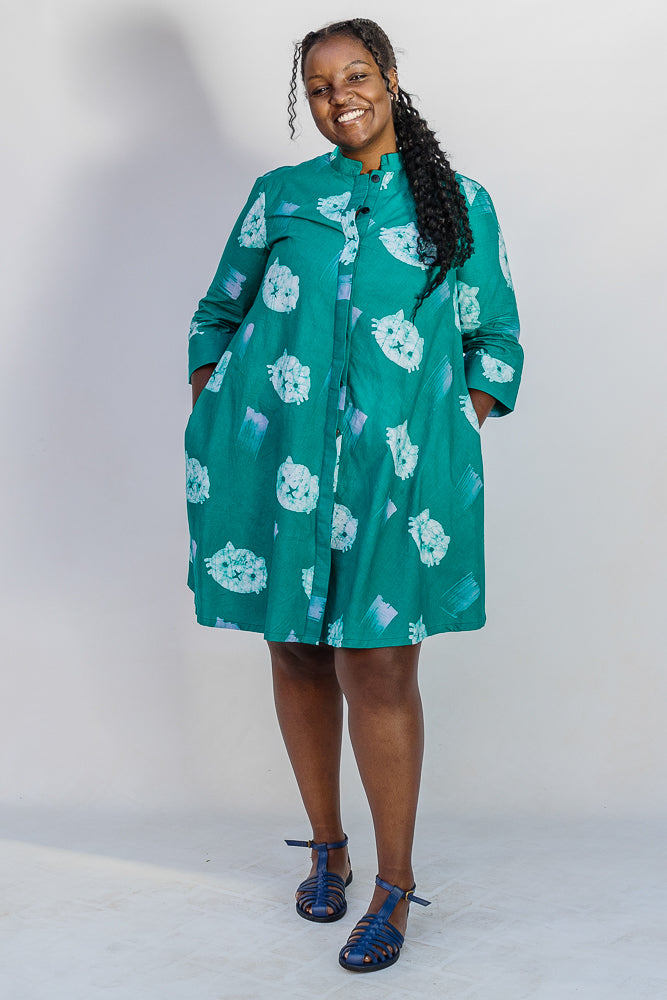 Model wearing teal dress with white cat print.