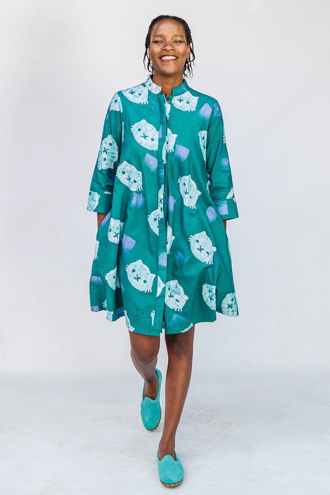 Model wearing teal dress with white cat print.