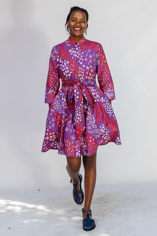 Model wearing purple dress with red and white floral print.