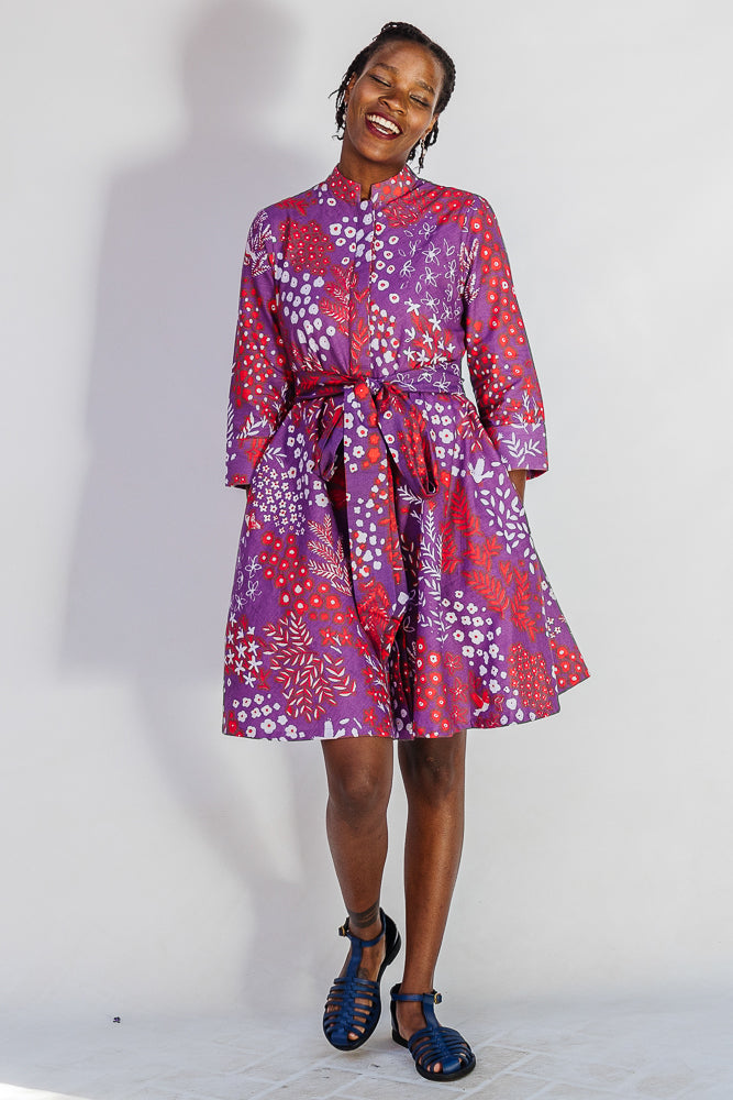 Model wearing purple dress with red and white floral print.