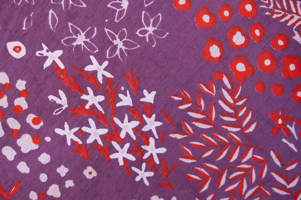 Close up display of purple dress with red and white floral print, fabric.