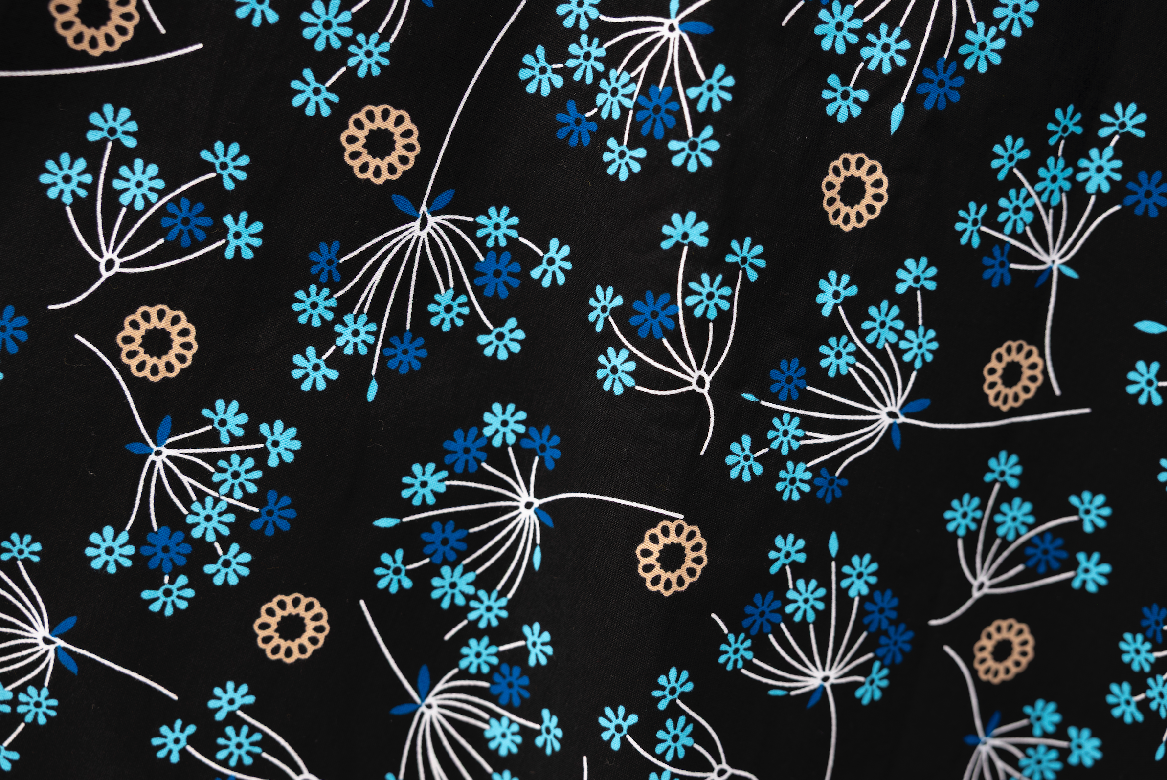 Close up display of black dress with blue and beige floral print, fabric.