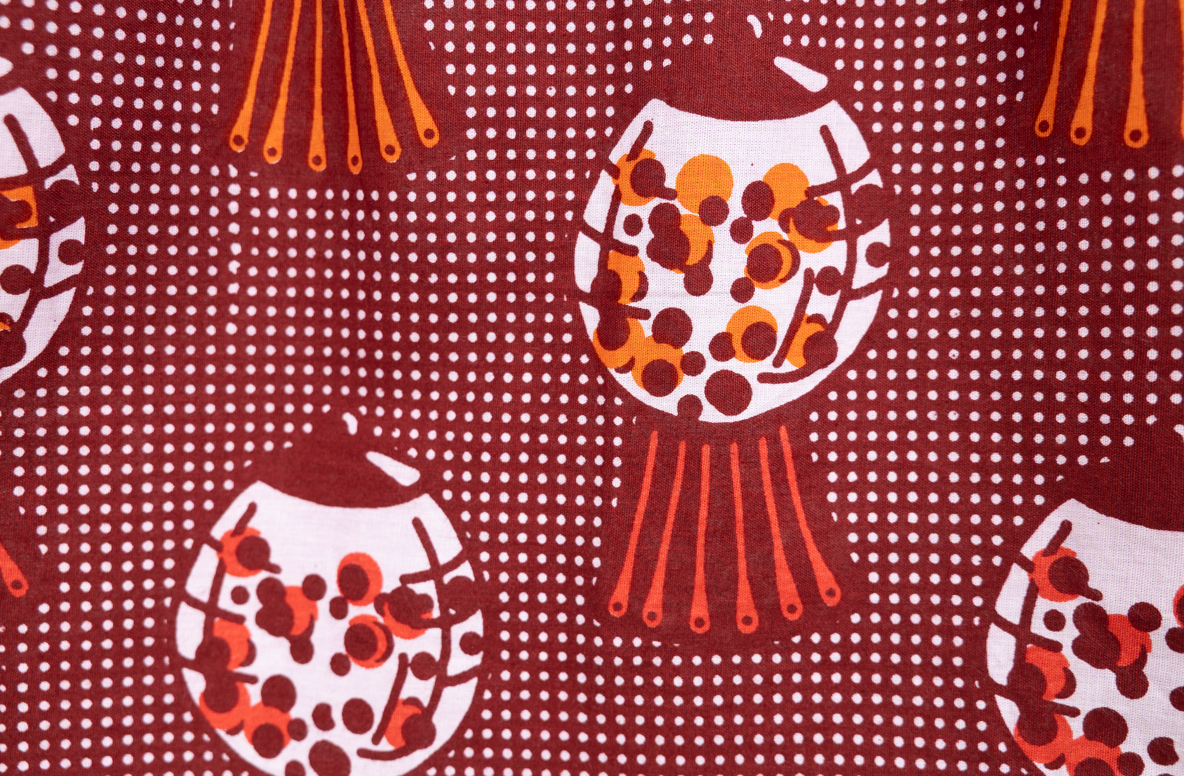 Close up display of red shirt with orange and white gumball print, fabric.