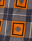Close up display of orange, navy and white geometric print shirt, fabric.