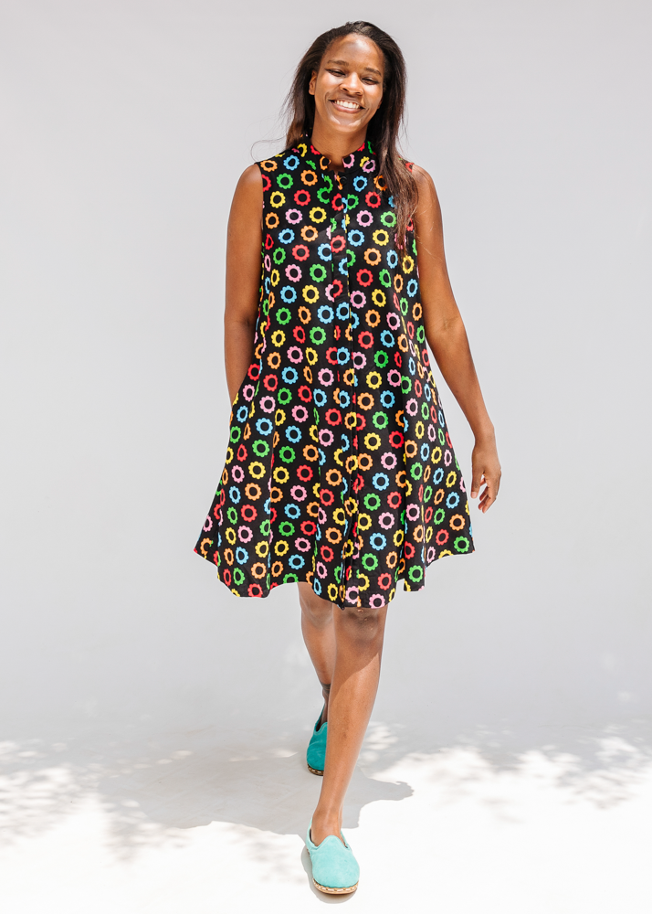 Model wearing black sleeveless dress with rainbow circle print.