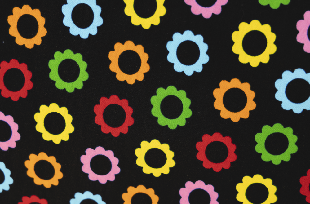 Close up display black sleeveless dress with rainbow circle print, fabric.