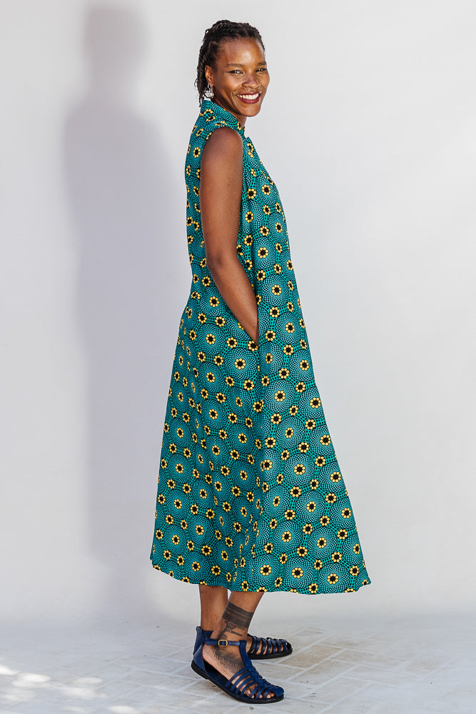 Model wearing teal dress with yellow sunflower print.