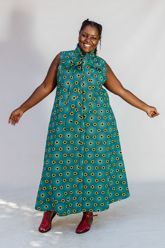 Model wearing teal dress with yellow sunflower print.
