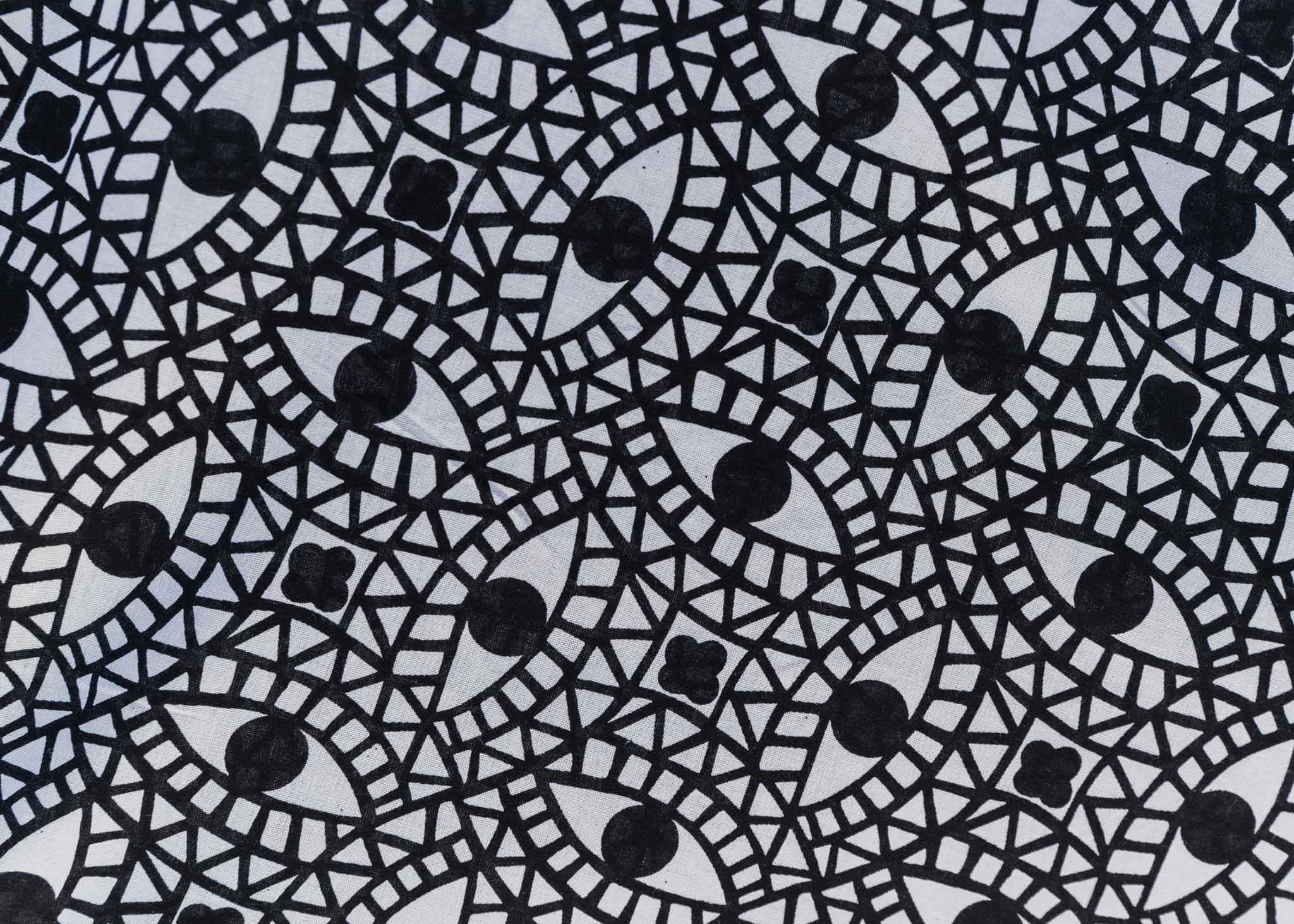 Close up display of black and white dress with mosaic eye pattern, fabric.