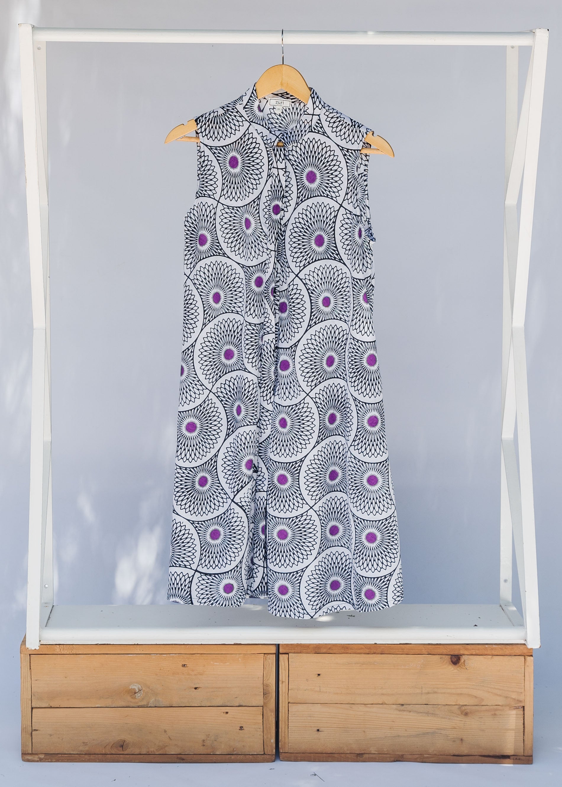 Display of white sleeveless dress with large black and purple floral print.