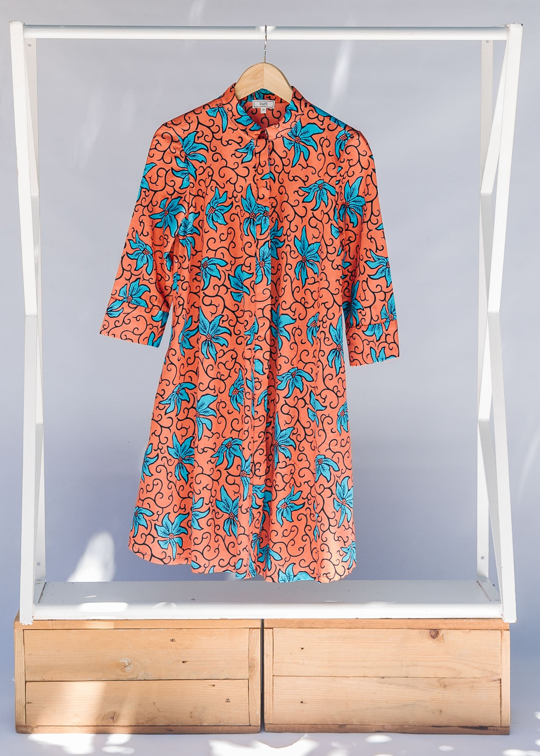 Display of orange dress with teal floral print.