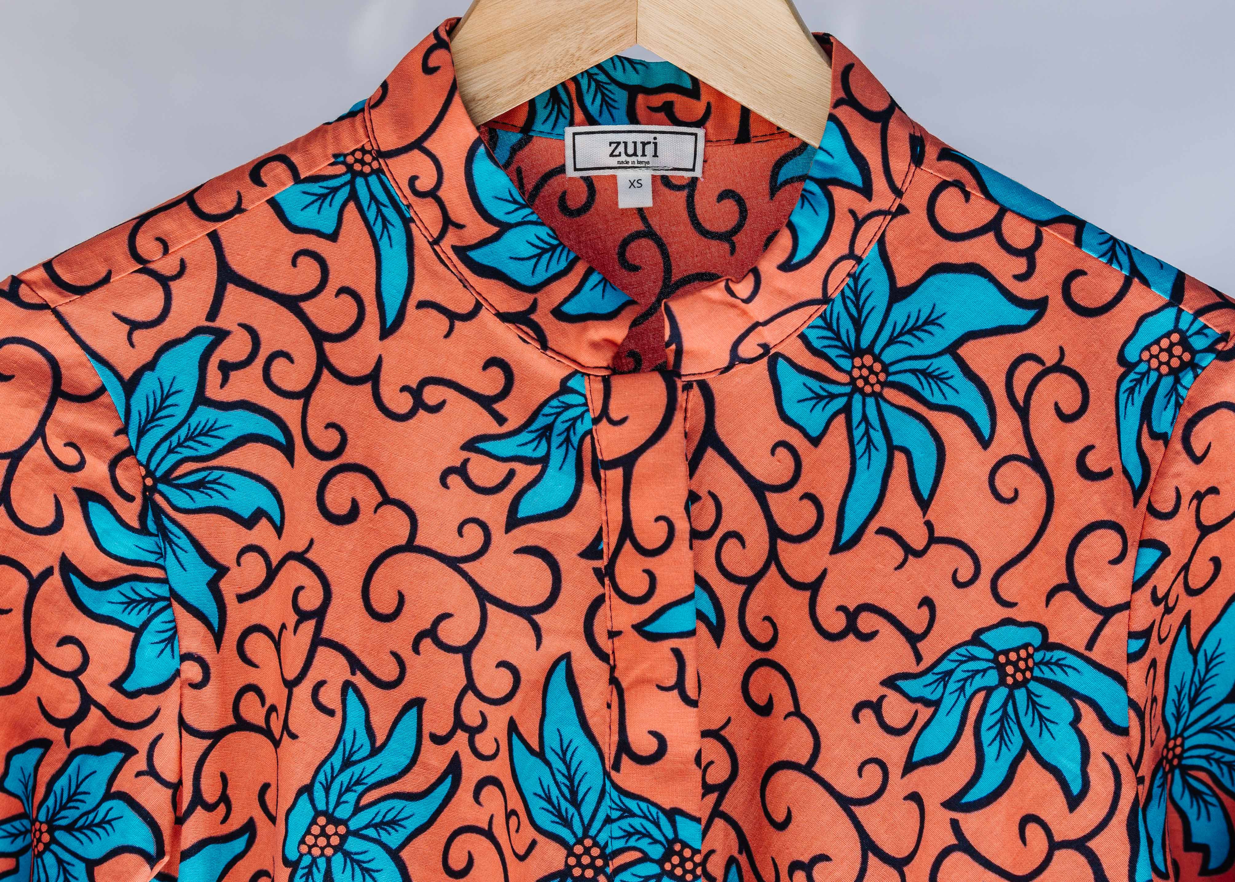 Display of orange dress with teal floral print.